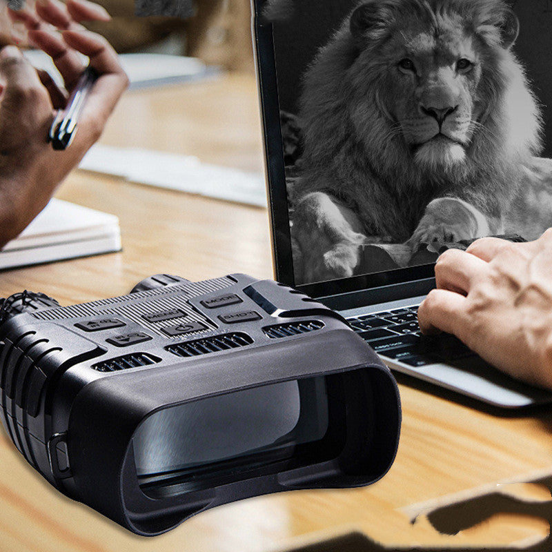 Person using a laptop with a lion image on the screen, next to a black electronic device on a wooden table.